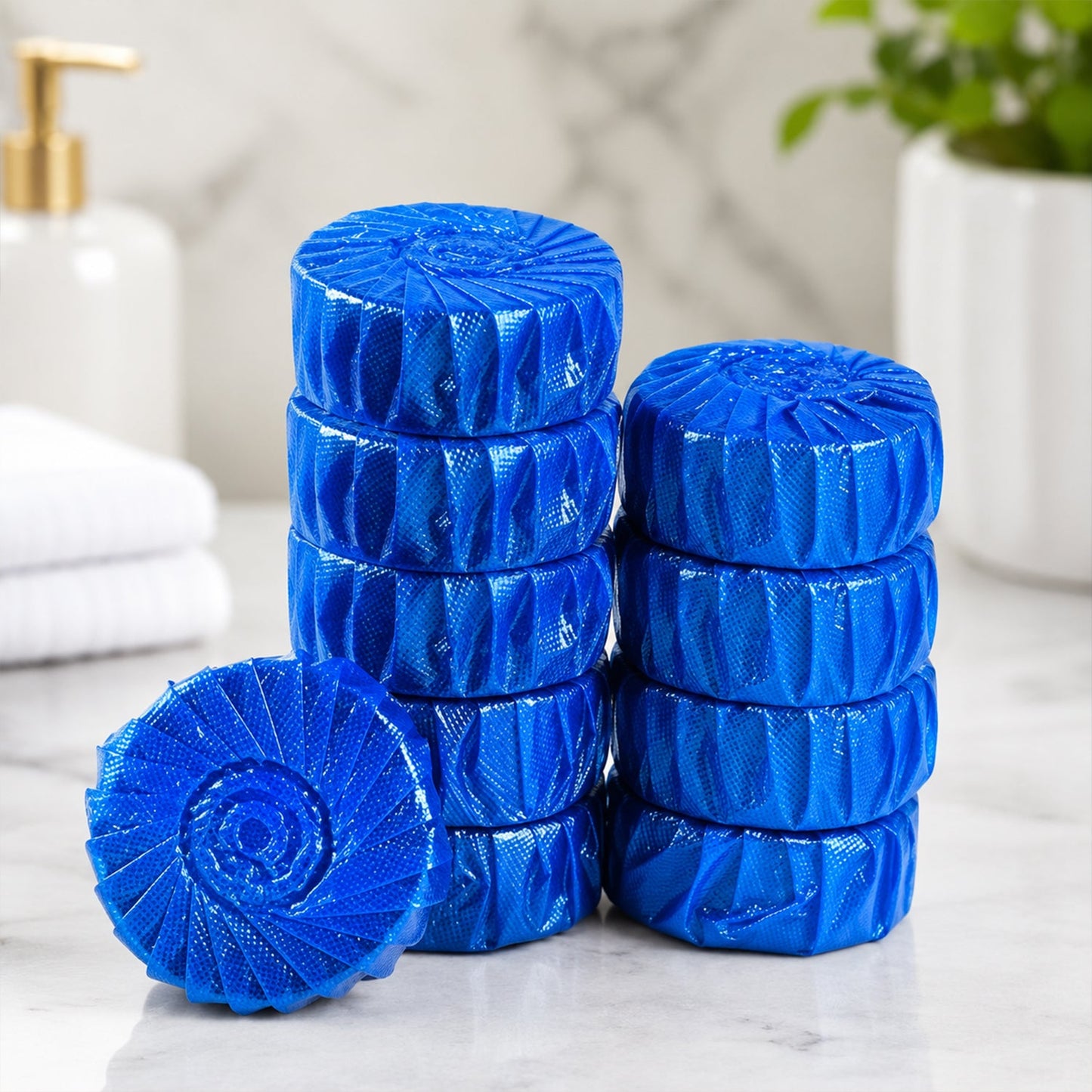 Ten blue toilet cleaner tablets, some stacked, are displayed on a white marble surface in a bathroom setting.