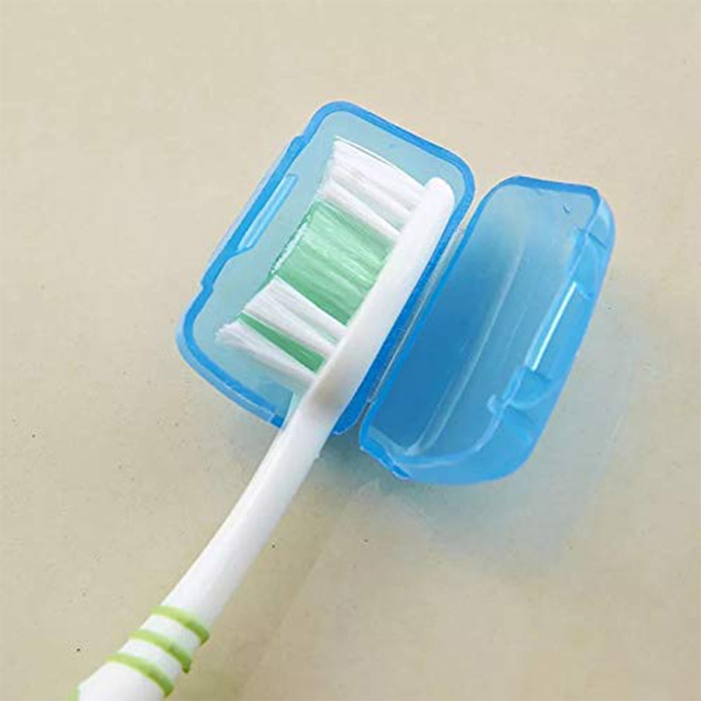 A blue translucent toothbrush head cover is open, revealing a white toothbrush with green and white bristles.
