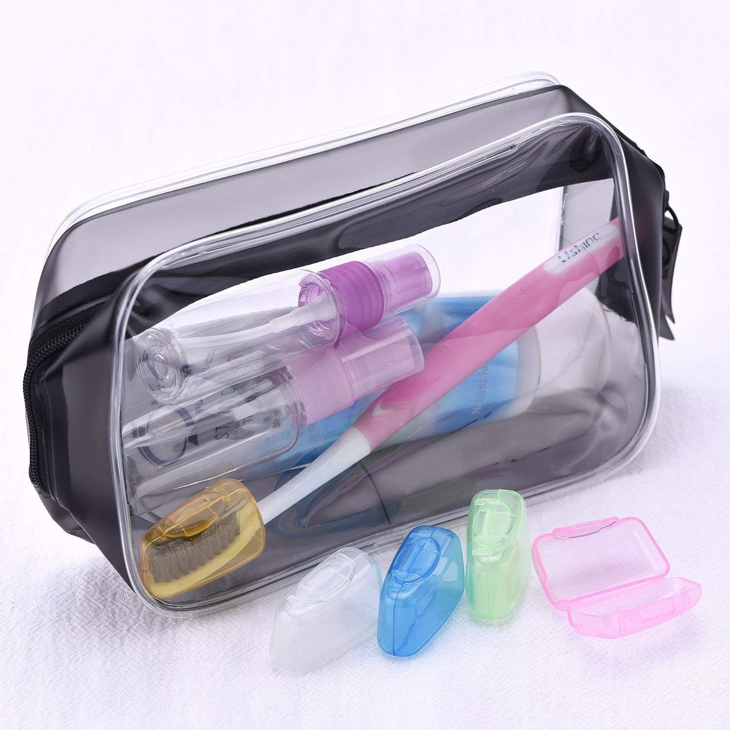 A clear travel bag holds toiletries, including a toothbrush with a yellow head cover, and four other covers are outside.