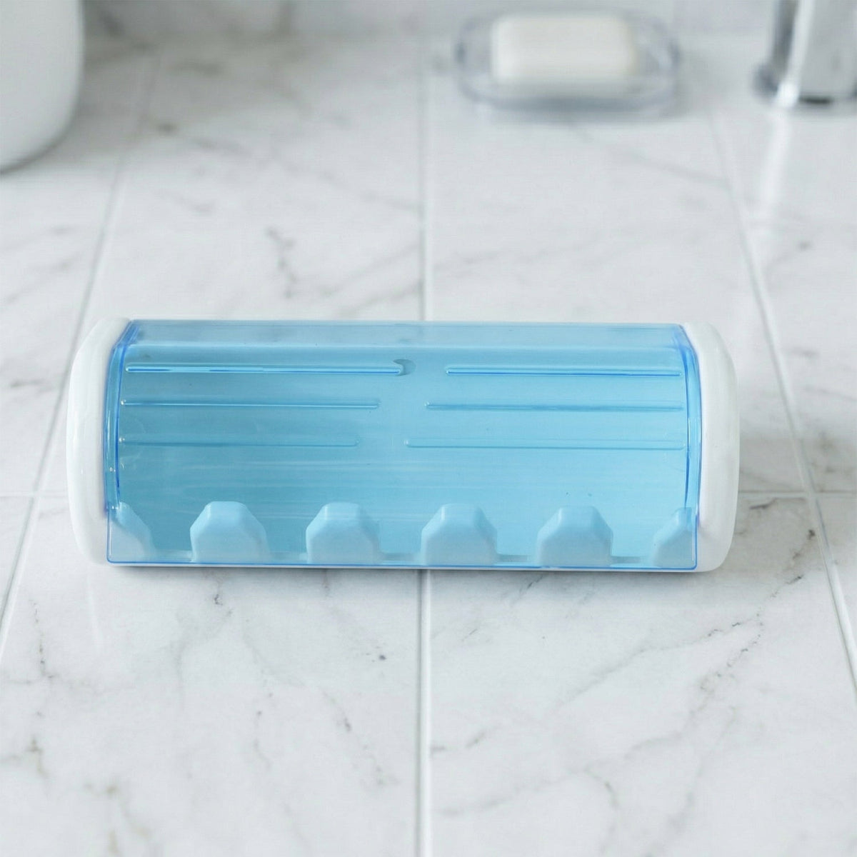 White and blue toothbrush holder on a white marble countertop in a bathroom setting.