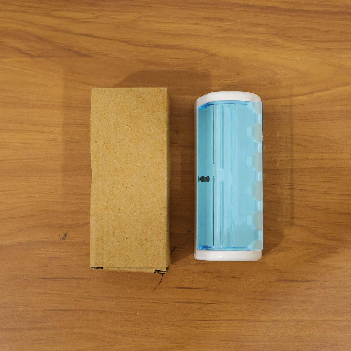 A white and blue toothbrush holder next to a brown cardboard box on a wooden surface