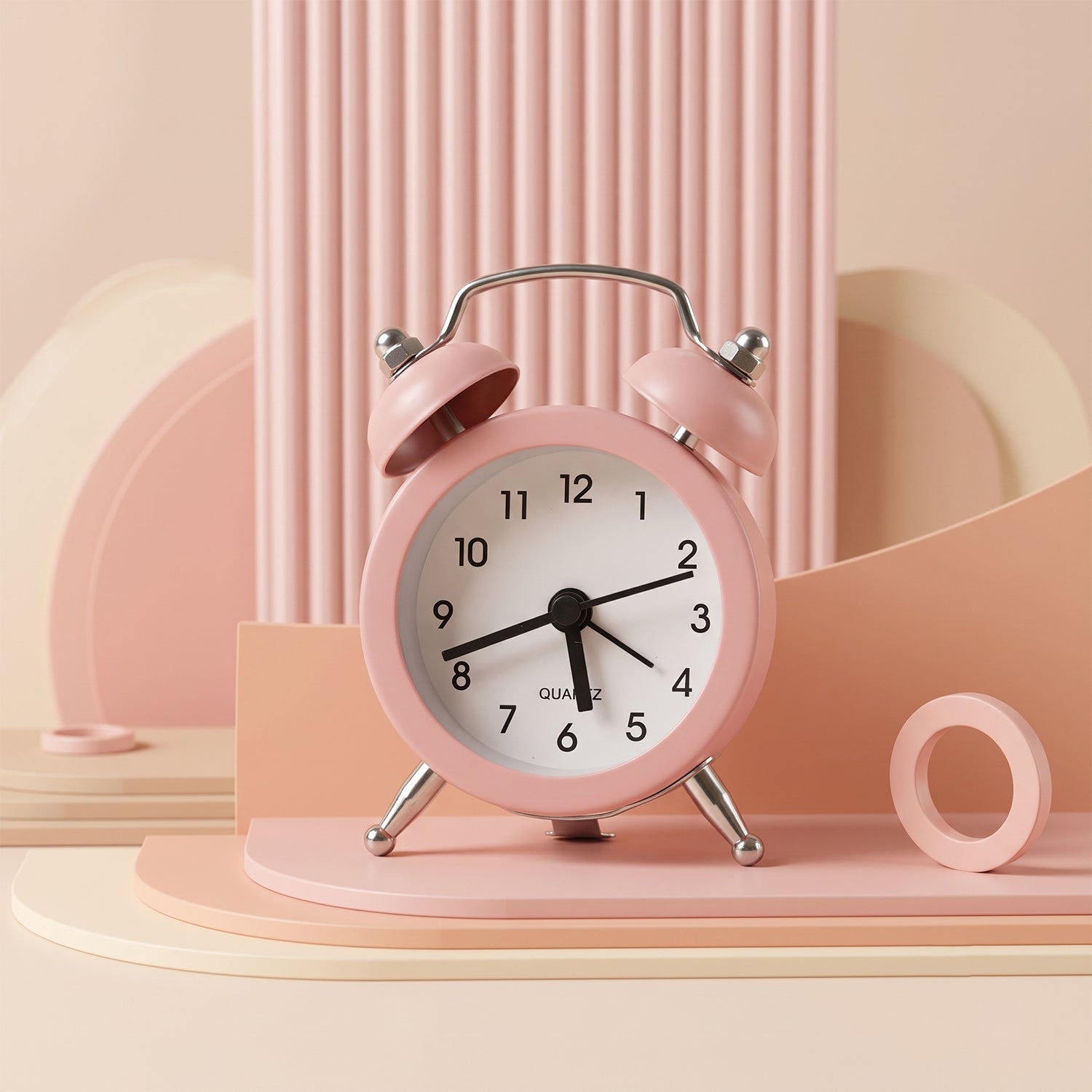 Pink twin bell alarm clock displayed on a multi-tiered pink and beige geometric background.