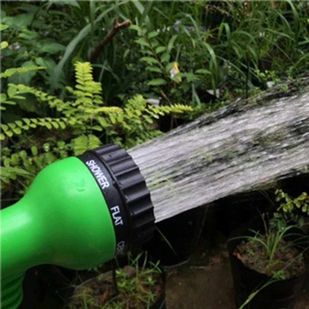 Close-up of a green and black hose nozzle spraying water with the
