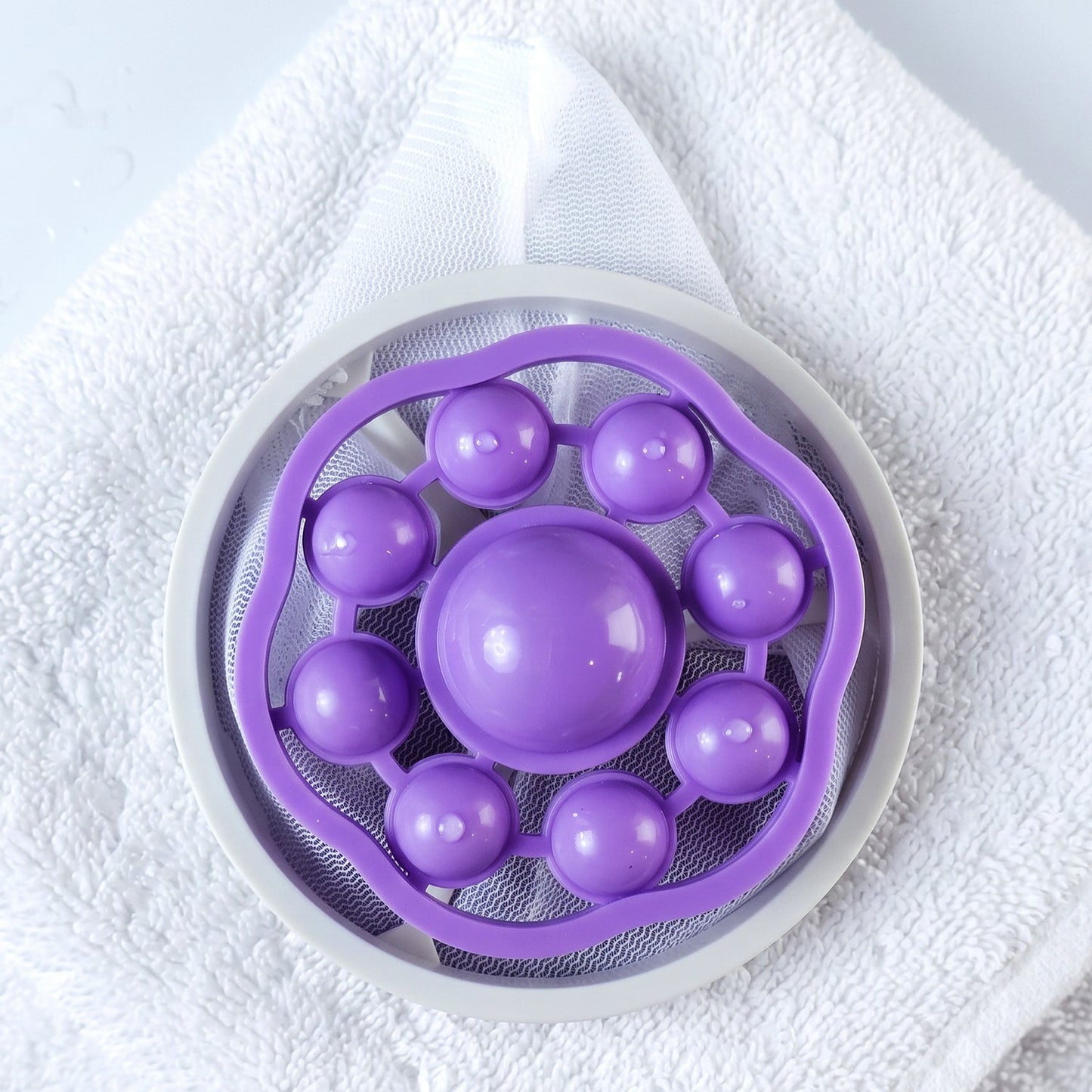 The top view of a purple and white floating lint mesh bag resting on a white towel.