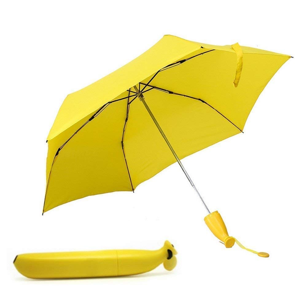 An open yellow umbrella with a banana-shaped handle and its matching closed case are arranged on a white surface.