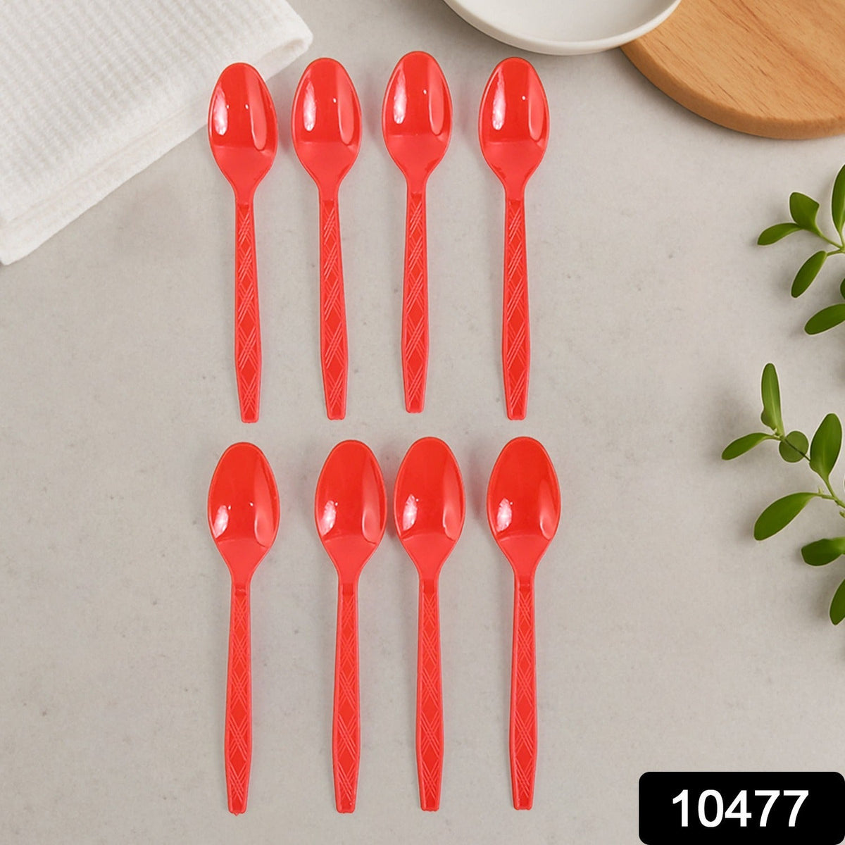 Eight red plastic spoons with textured handles laid out in two rows on a light gray surface.