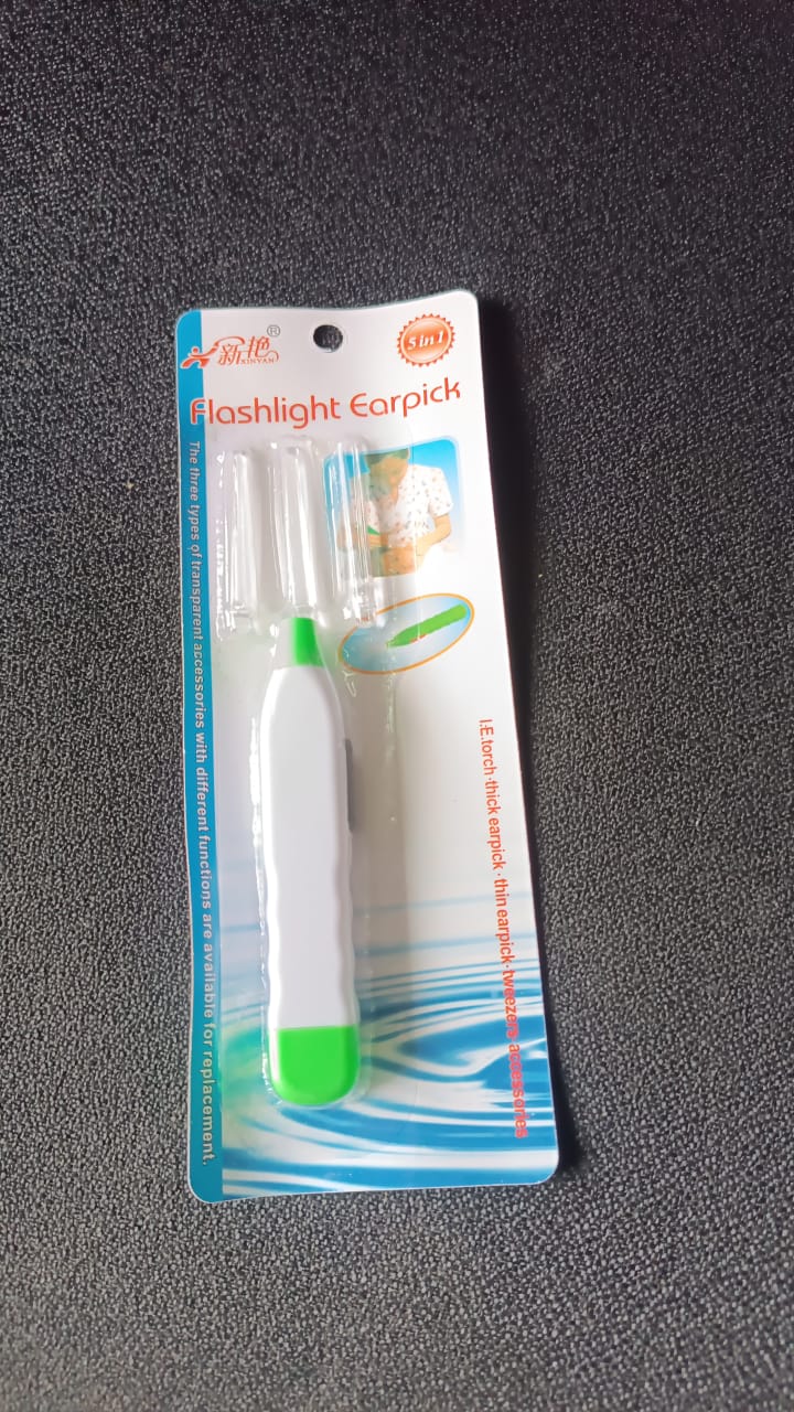 A packaged white and green flashlight earpick with interchangeable tips is displayed on a dark surface.