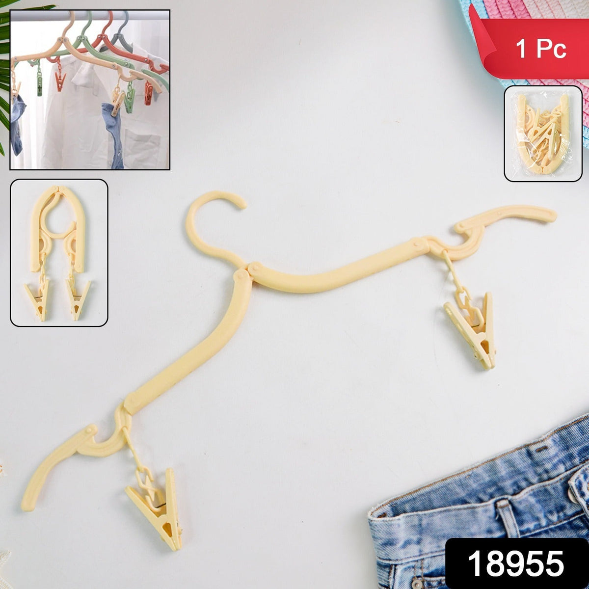 A beige foldable clothes hanger with two clips lies on a white surface next to blue jeans and a hat.