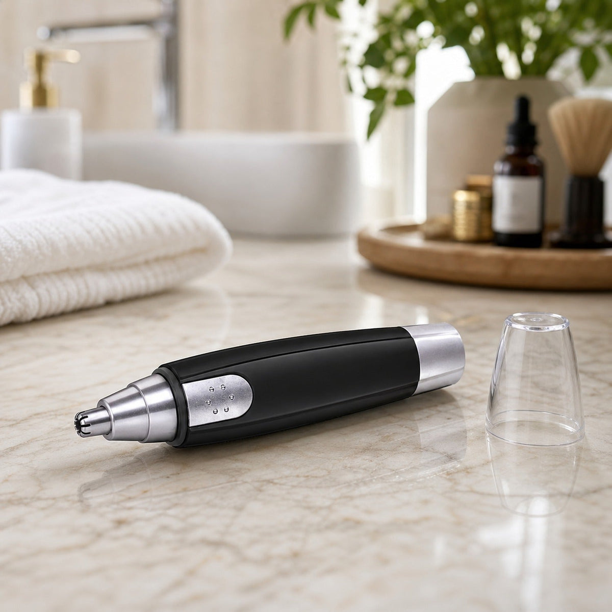 A black and silver nose hair trimmer lies on a marble counter with its clear cap next to it.