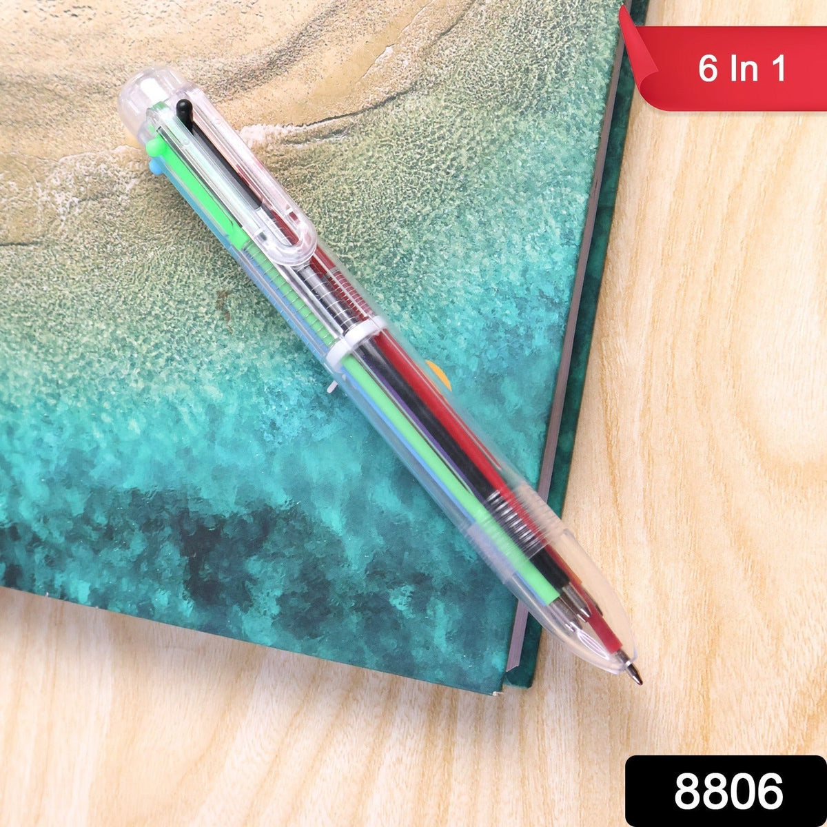 A clear 6-in-1 multicolor ballpoint pen with various ink colors is on a teal and brown surface, with a "6 In 1" label.