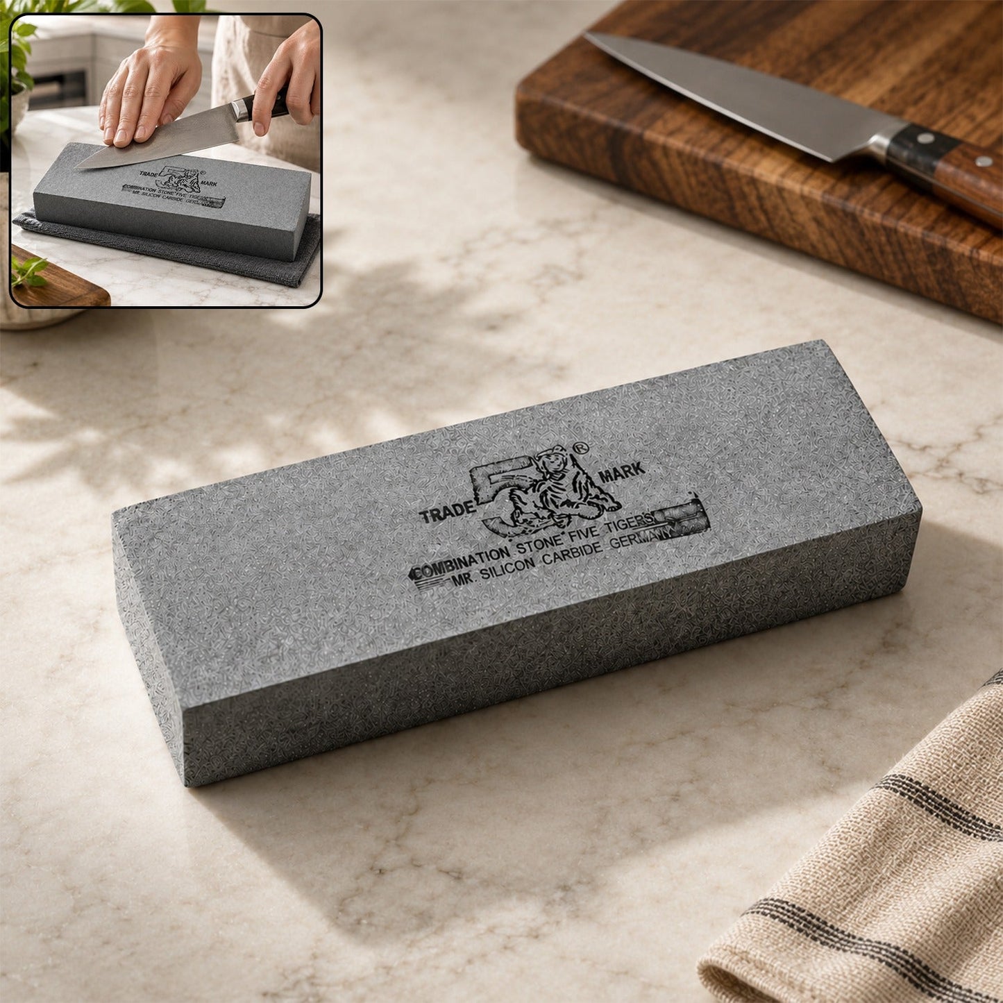 A gray silicon carbide whetstone sits on a white marble counter with a cutting board and knife in the background.