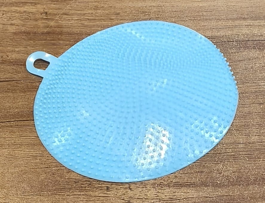 Kitchen setting featuring blue silicone dish scrubber for cleaning