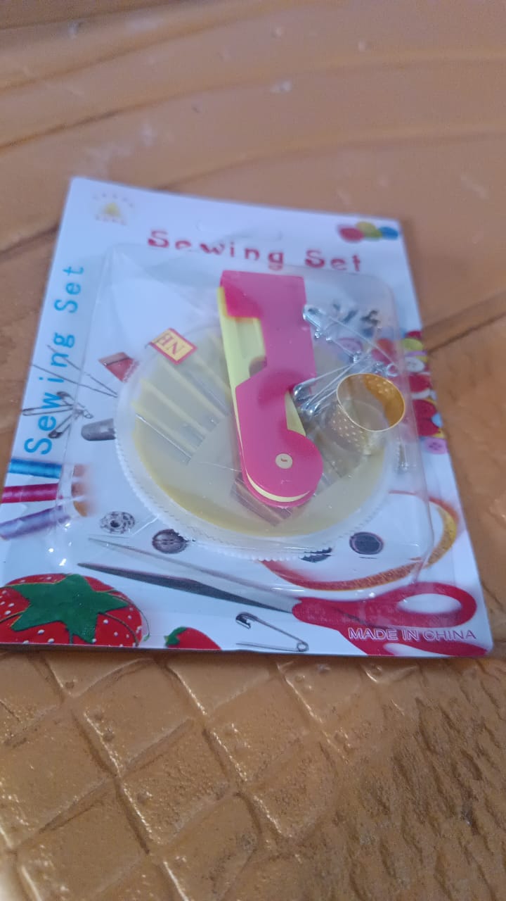 A packaged sewing set including a needle threader, needle disc, and thimble, with text "Sewing Set".