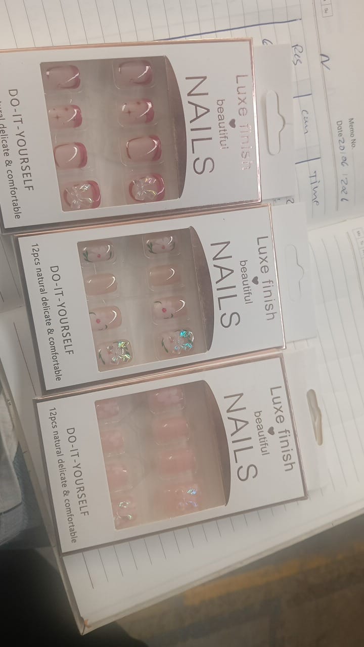 Three boxes of Luxe Finish Beautiful Nails, each containing 12 nude press-on nails with different designs, on a desk.