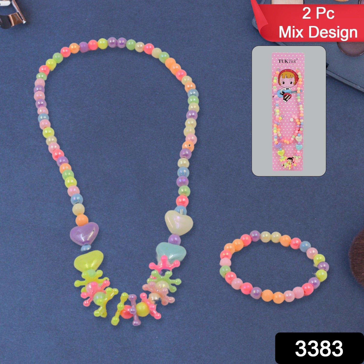 A colorful beaded necklace and bracelet set with heart and star-shaped beads is displayed on a dark blue surface next to its