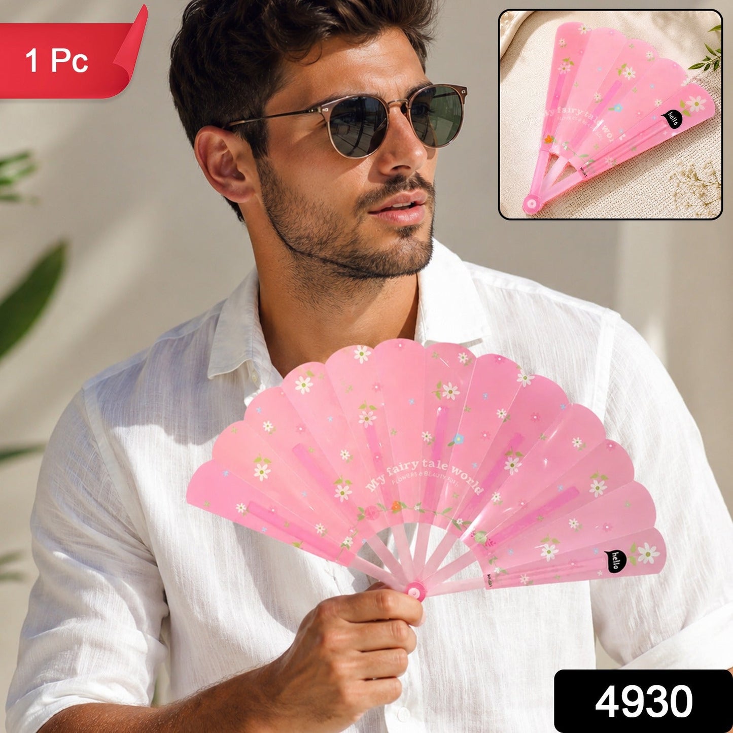 A man in a white shirt and sunglasses holds an open pink fan with white flowers and text, with a small folded fan in the top