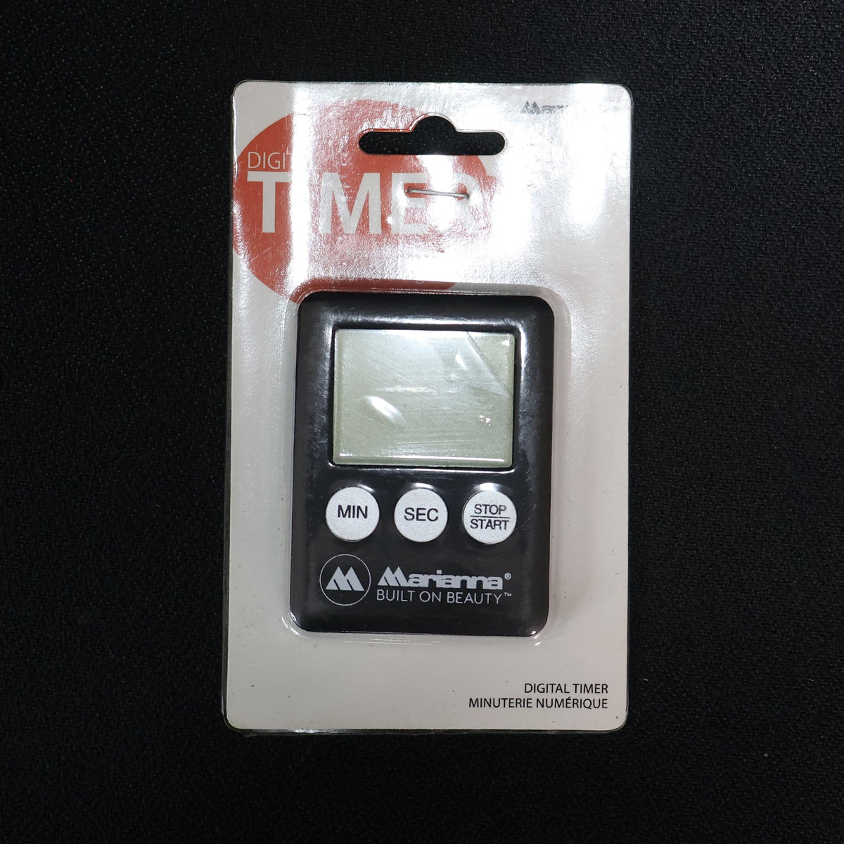 A black digital timer with a blank screen and three white buttons, sealed in clear retail packaging on a dark background.