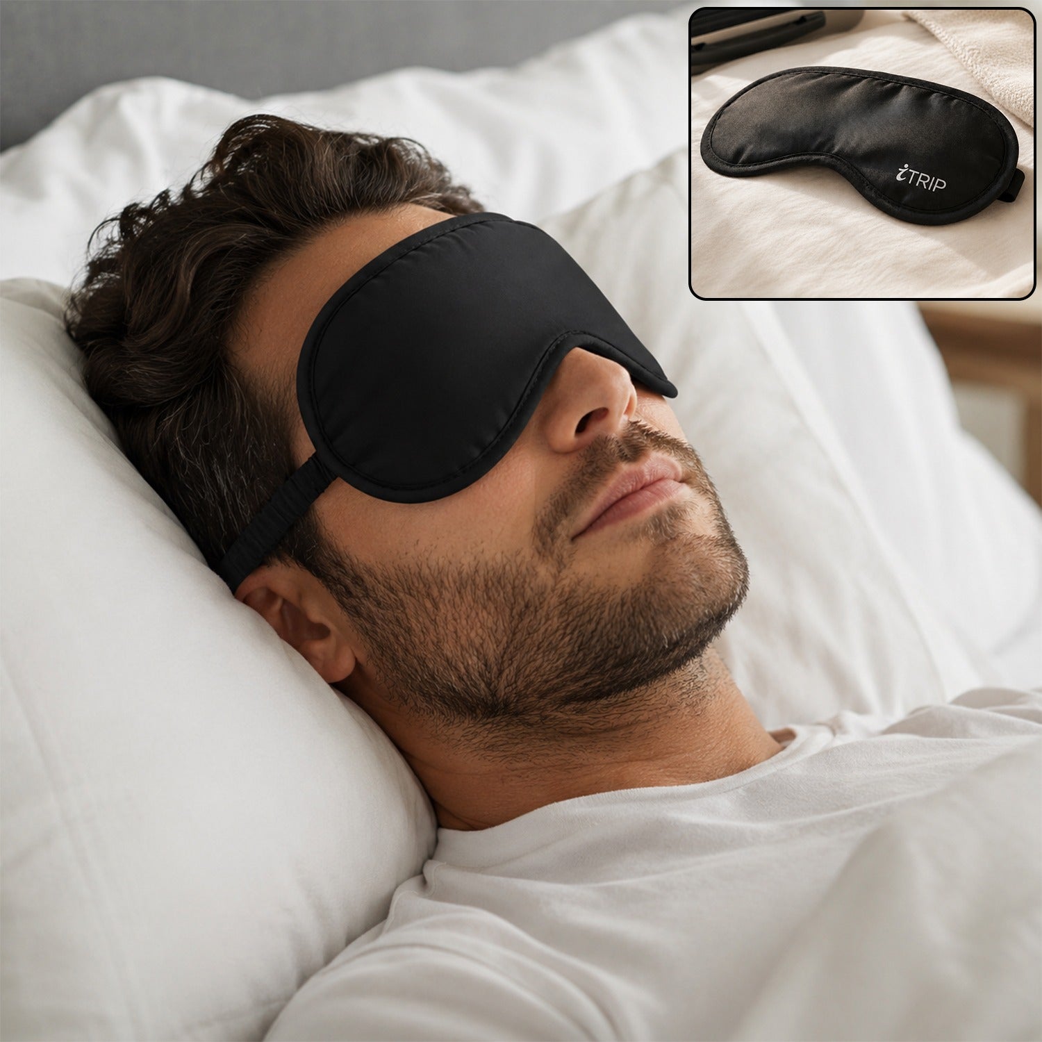 A man with a beard sleeps peacefully on a white pillow, wearing a black sleeping eye mask with an adjustable strap.