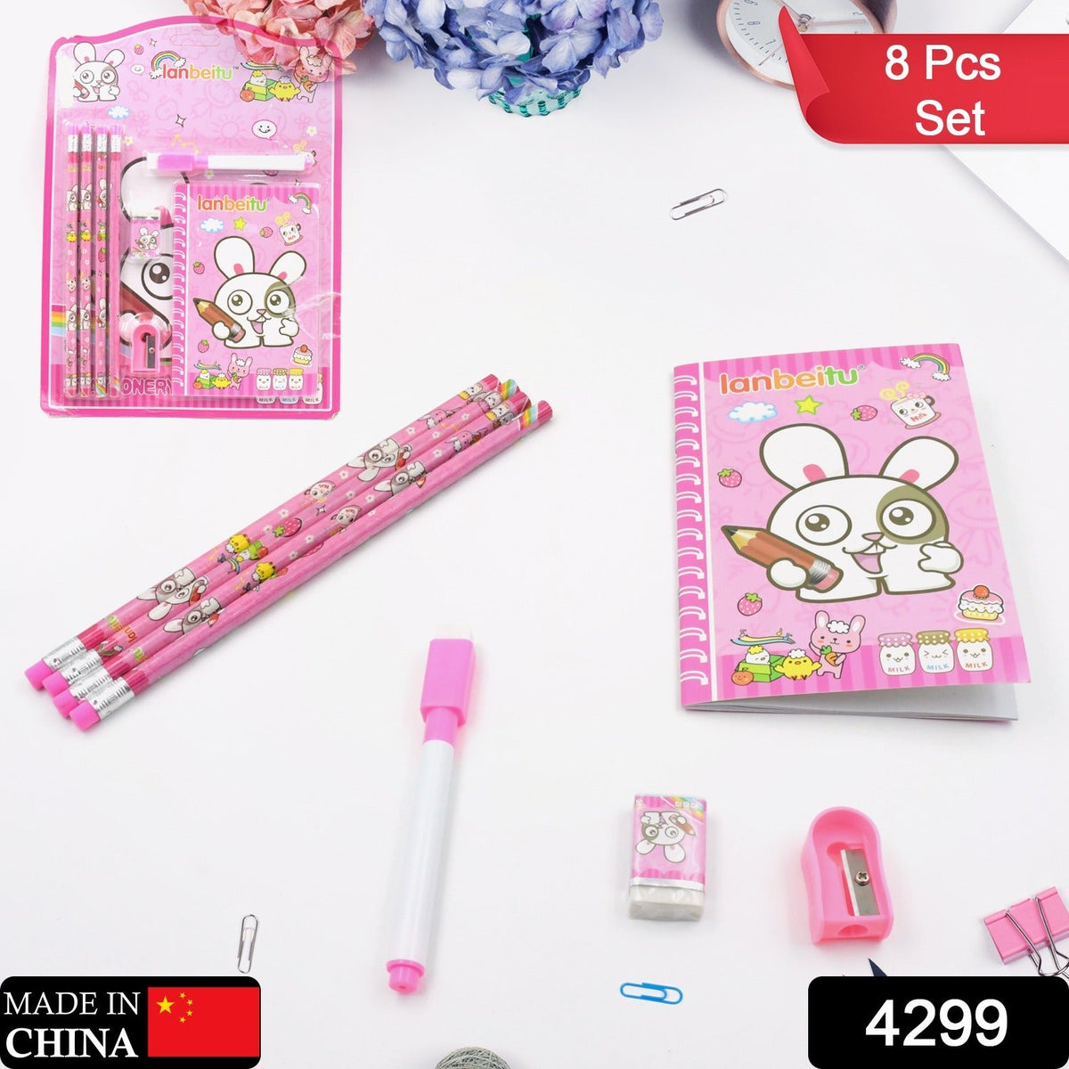 The pink bunny stationery set is laid out on a white surface with small office clips and a floral background.
