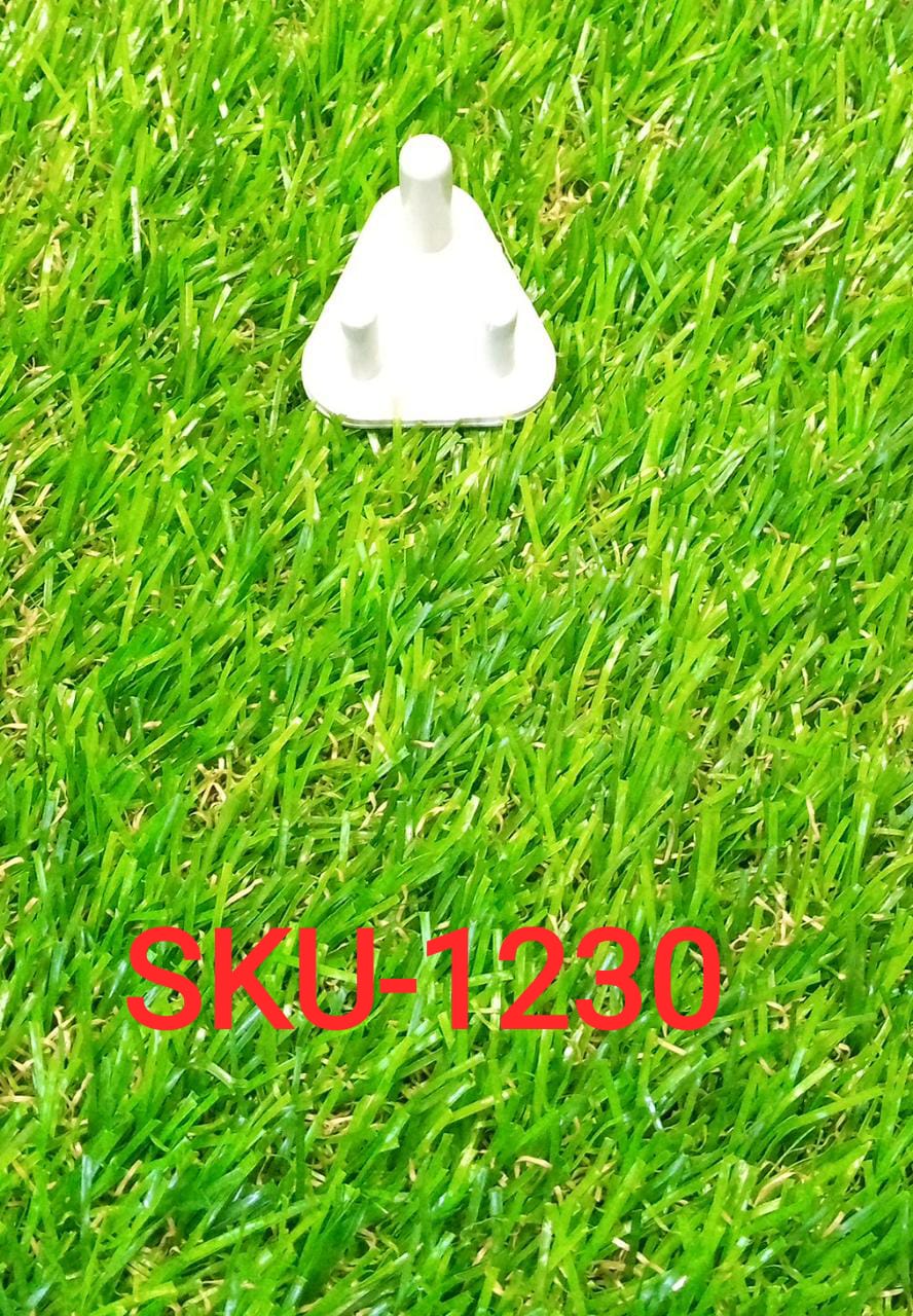 A single white child-proof plug with three prongs resting on bright green artificial grass.