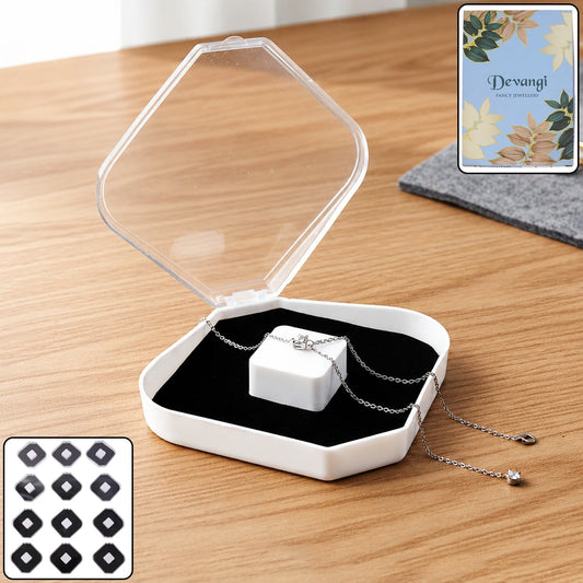 An open clear and white jewellery box with a silver necklace on a black velvet cushion, on a wooden table.