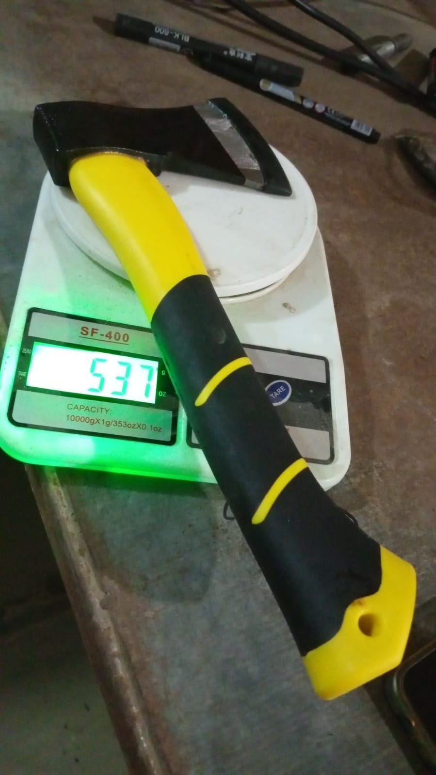 The yellow and black hatchet axe is being weighed on a digital scale, displaying 537 grams.