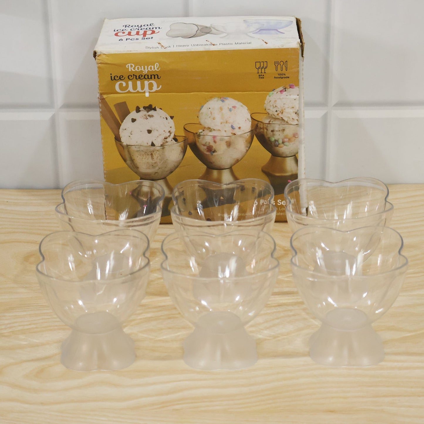 Nine clear plastic dessert bowls with heart-shaped rims and frosted bases, in front of a 'Royal ice cream cup' box.