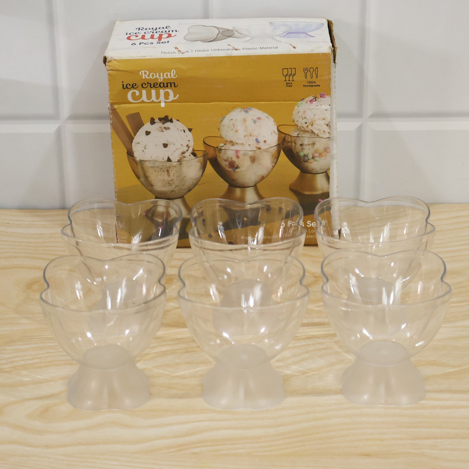 Nine clear plastic dessert bowls with heart-shaped rims and frosted bases, in front of a 'Royal ice cream cup' box.