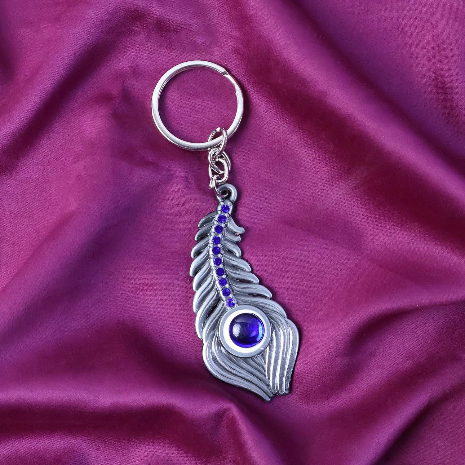 Stylish metal keychain with peacock feather motif and blue gem