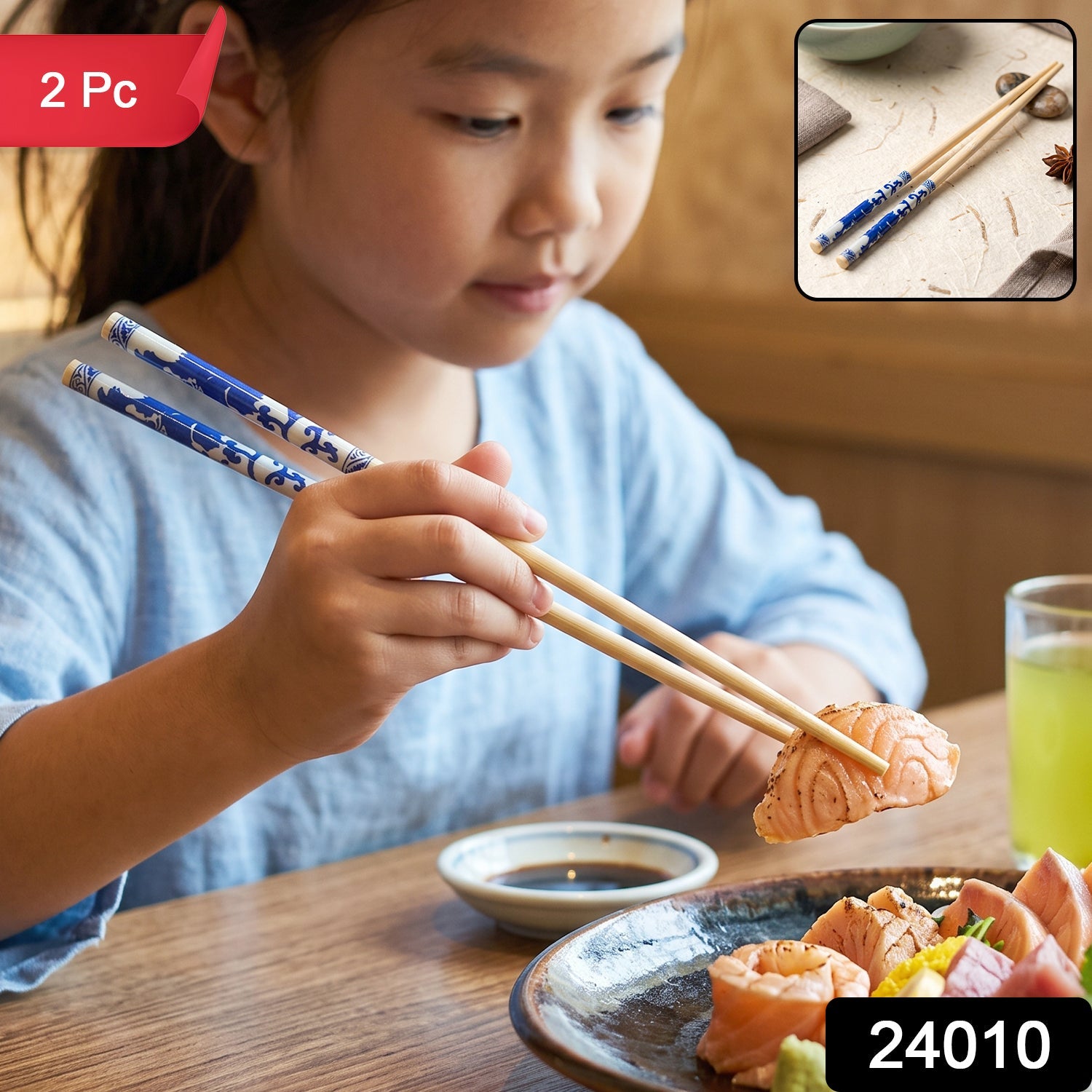 A young girl in a blue shirt uses bamboo chopsticks with blue Chinese print to pick up a piece of salmon. (2 Pc)