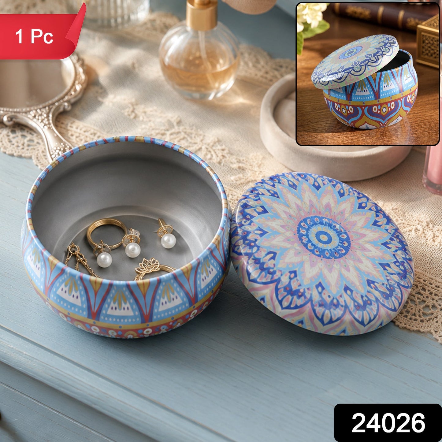 A round metal mandala tin box with its lid resting beside it on a blue dresser, displaying jewelry inside.