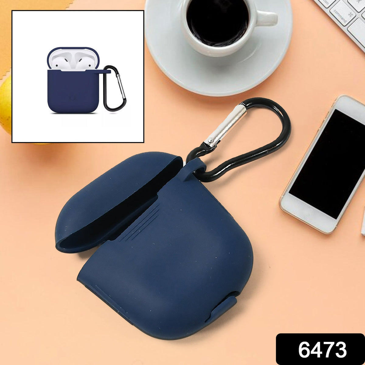 A navy blue silicone earbud case with an open lid and black carabiner sits on a peach surface.