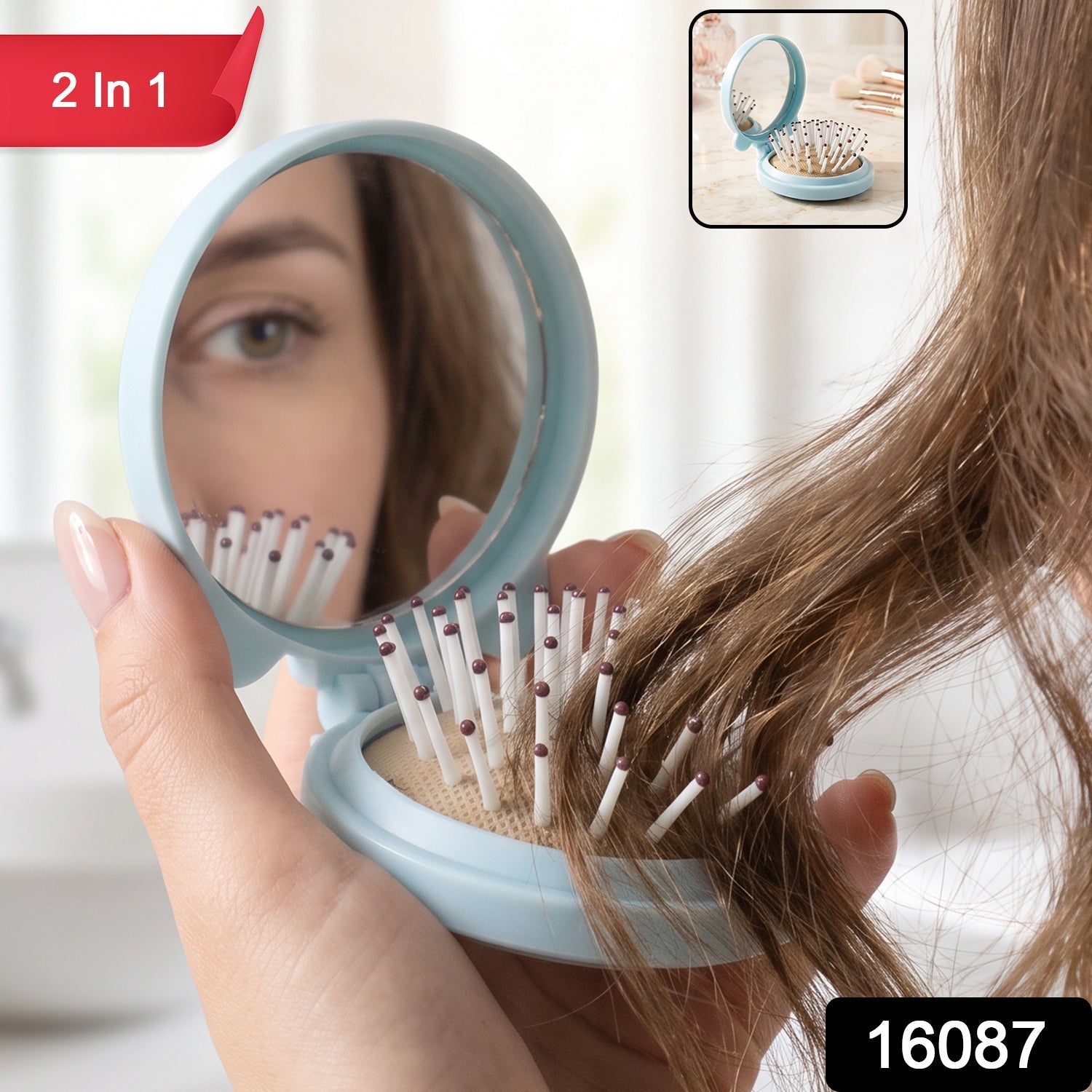 A woman's hand holds a light blue folding hairbrush with a mirror, reflecting her eye and the brush bristles, with a '2 in