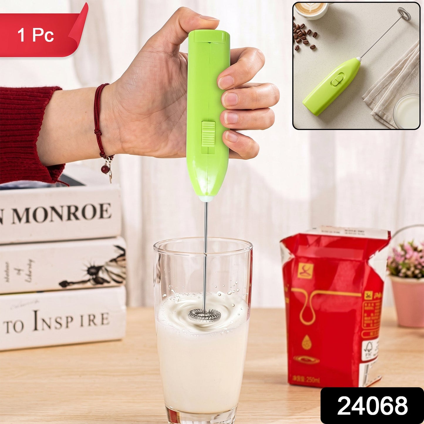 A hand holds a bright green electric frother, mixing milk in a clear glass, with books and a milk carton in the background.