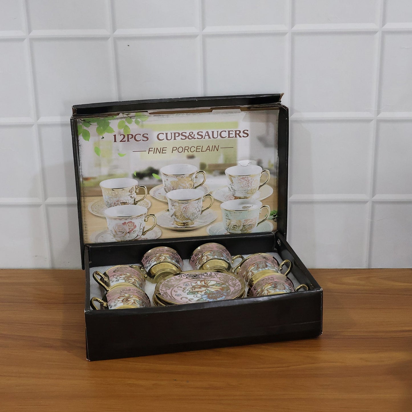 A black box containing six pink and gold floral porcelain teacups and saucers, with an image of more sets on the lid.