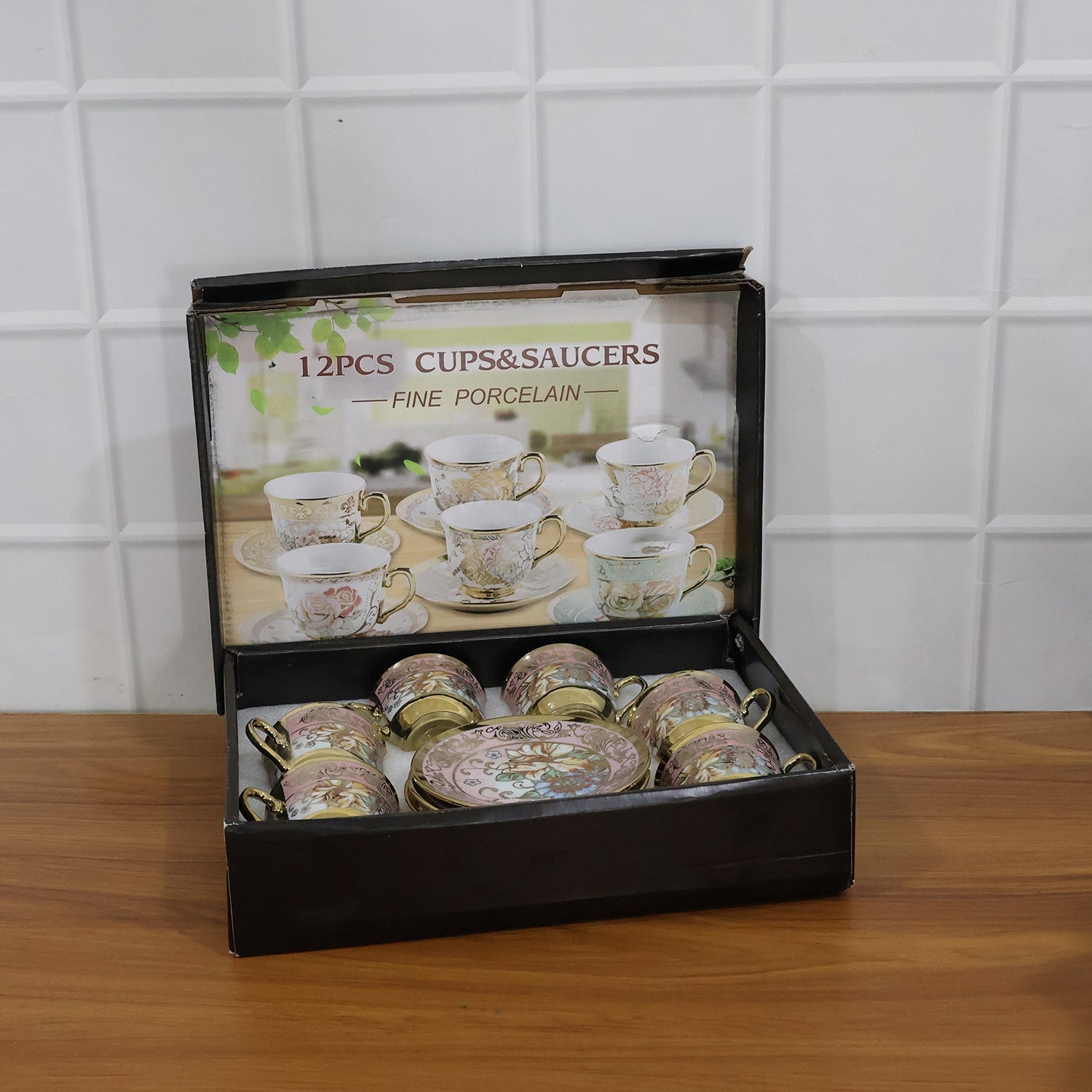 A black box containing six pink and gold floral porcelain teacups and saucers, with an image of more sets on the lid.