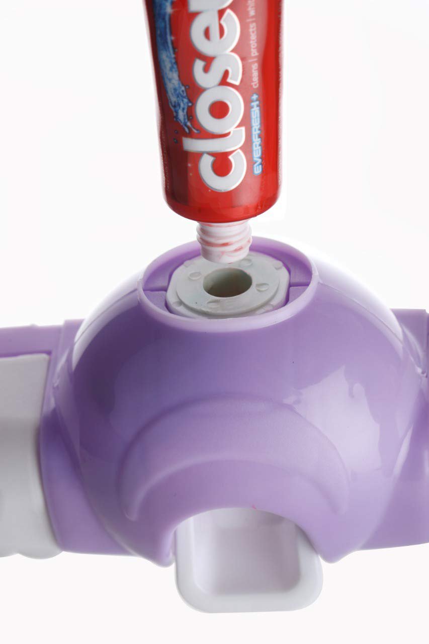 Close-up of a purple toothpaste dispenser with a red toothpaste tube inserted, showing the internal mechanism.